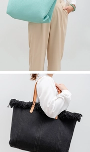 Close-up of woven tote bags in light blue and black with leather handles and fringe details