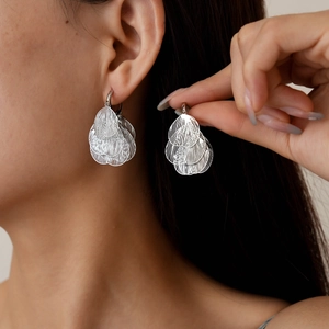 Chic silver hollow heart petal earrings worn by a model to show layered leaf design