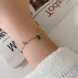 Golden titanium steel bracelet with colorful rainbow zircon charms on a woman wrist