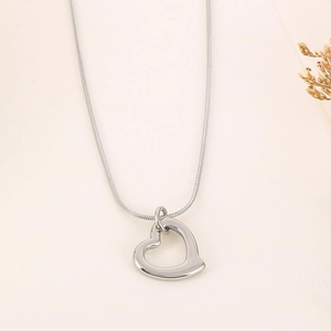 Minimalist silver heart hollow pendant necklace with sleek snake chain on beige surface