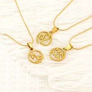 Three gold zodiac necklaces with hollow pendant charms on textured white woven background