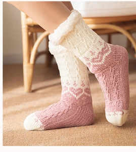 Detail of pink knitted floor socks with white fuzzy fleece lining and heart patterns