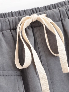 Detail of grey cargo skort featuring elastic waist and thick cream woven drawstrings