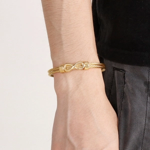 Macro detail of golden infinity symbol knot on twisted metal rope bracelet for men