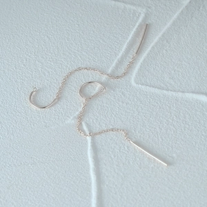 Macro shot of polished 925 silver C-shaped long tassel chain earrings in rose gold finish