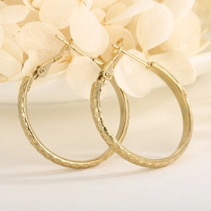 Macro view of gold hoop earrings featuring a sophisticated diamond pattern texture
