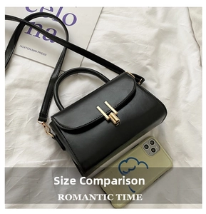 Detail of black faux leather mini bag with gold H-shaped buckle and magazine contrast