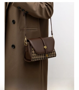 Detail of houndstooth patchwork shoulder bag with leather strap on a brown coat