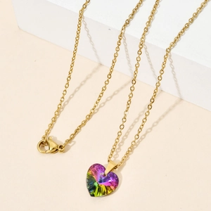 Close-up of gold heart necklace with rainbow zircon on white geometric display stand