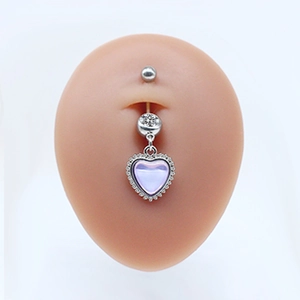 Detailed view of navel ring with purple heart-shaped gem and clear crystal on model