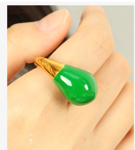 Close-up of golden titanium ring featuring a glossy green teardrop-shaped gemstone inlay