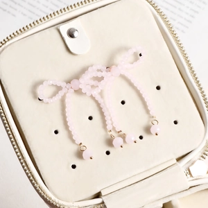 Close-up of pink beaded bow earrings with dangling beads inside a white jewelry box