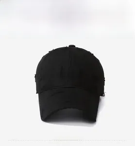 Close-up of a black distressed baseball cap showing torn details and frayed cotton fabric