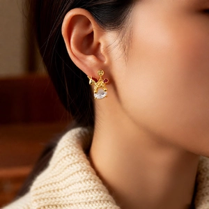 Detailed view of 18k gold plated horse earring with red enamel and drop zircon on model