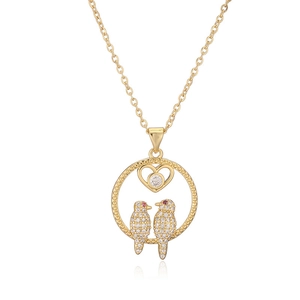 Macro shot of gold-plated bird pendant with cubic zirconia heart and fine chain