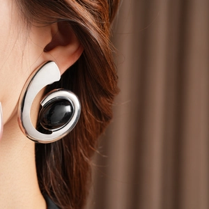 Detail of vintage silver spiral earring with a black oval stone on a model's ear