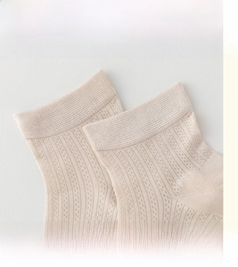 Detailopname van de elastische geribbelde boord van een beige zijden mix sok