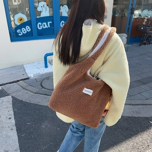 Brown teddy fleece tote bag with white label shown on a model in outdoor street style