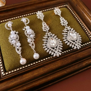 Detail of luxury rhinestone wheat-shaped pearl earrings on a green velvet display