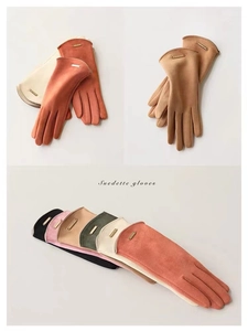 Close-up of various colored suedette gloves showing metal logo details and soft fleece lining