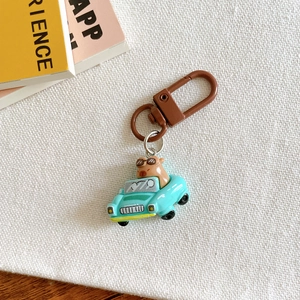 Close-up of a cute capybara in a blue car keychain on a cozy fabric background