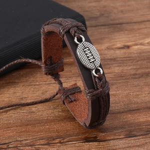Macro detail of men's woven leather bracelet with silver-tone rugby ball metal charm