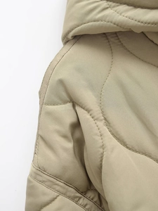 Detail of khaki quilted jacket featuring wavy stitching and fine textured fabric