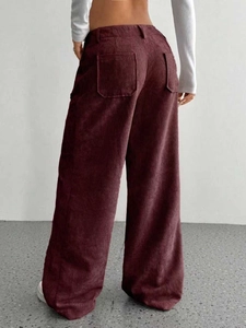 Dettaglio dei pantaloni larghi in velluto a coste bordeaux con tasche e trama verticale
