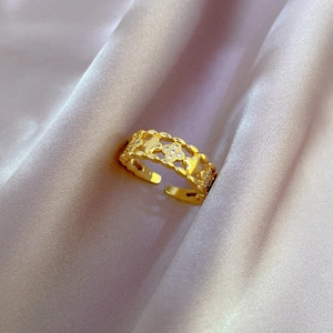 Macro shot of gold four-leaf clover ring with zircon inlay on purple silk background