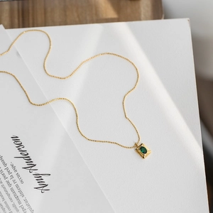 Minimalist gold necklace featuring a square green crystal pendant on a fine bead chain