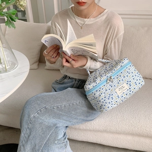 Détail d'une trousse de maquillage matelassée à fleurs bleu clair avec fermeture éclair