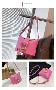 Detail showing the pink leather surface and large golden D-shaped metal buckle on the bag