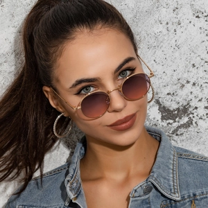 Close-up of oval metal sunglasses with purple gradient lenses and gold frames on model