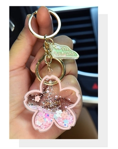 Detailed macro view of pink acrylic Sakura keychain with floating glitter and gold metal ring