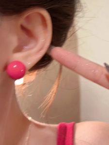 Detailed close-up showing a bright pink dopamine-style geometric earring on ear