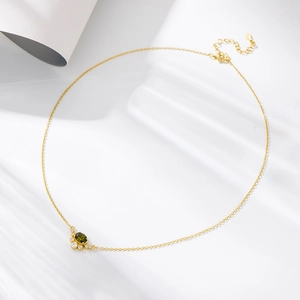 Close-up of gold necklace with oval olive green zircon pendant and crystal accents