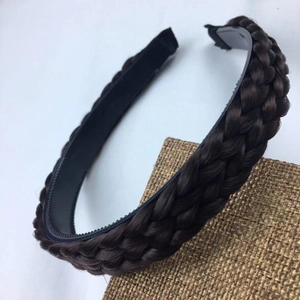 Close-up of deep brown braided headband with non-slip teeth on textured linen surface