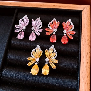 Detailansicht von drei Paaren Zirkonia-Ohrhängern in Pink, Orange und Gelb im Etui