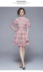Detailed close-up of pink layered lace dress showing ruffled hem and floral embroidery texture