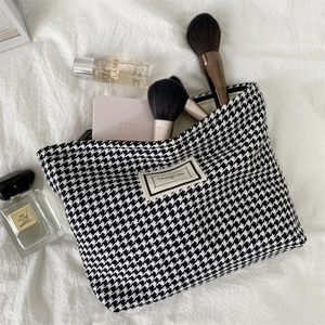 Close-up of houndstooth toiletry bag with zipper and Pleasant Time woven label