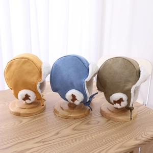 Detailed view of yellow, blue, and brown plush winter earflap hats for kids on wood stands