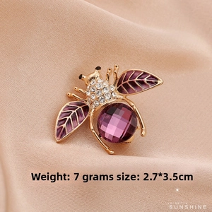 Detailed view of a gold-plated bee brooch with purple crystals and sparkling rhinestones