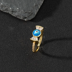 Macro detail of gold-plated evil eye ring with blue enamel and white zircon accents