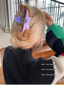 Detail view of a purple star-shaped hair claw clip on long hair with a matte finish