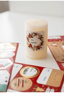 Detail view of festive Merry Christmas gift labels on a pillar candle with gold foil accents
