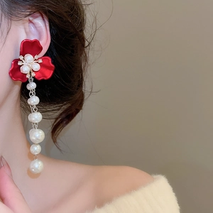 Close-up of elegant red flower earrings with cascading white pearls and sparkling rhinestones