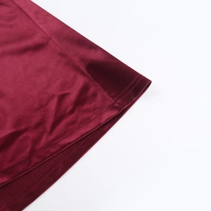 Détail d'une robe en satin bordeaux montrant la texture de soie et la couture fine