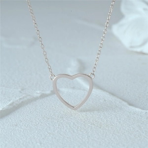 Detail of minimalist hollow heart pendant in S925 sterling silver on a subtle grey background