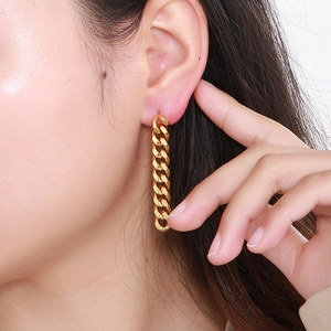 Close-up of golden long Cuban chain tassel earrings worn on model for a punk style look