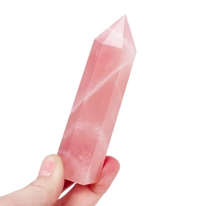 Natural rose quartz hexagonal crystal pillar held in hand on white background
